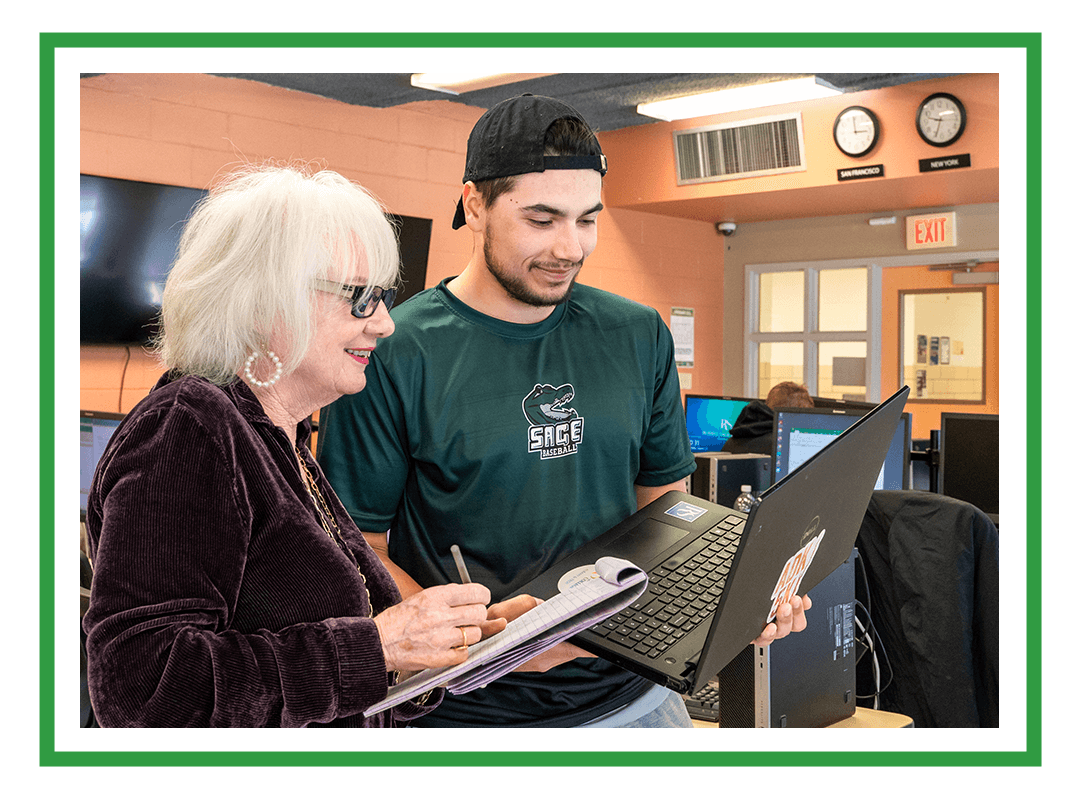 A student and professor looking at a laptop.