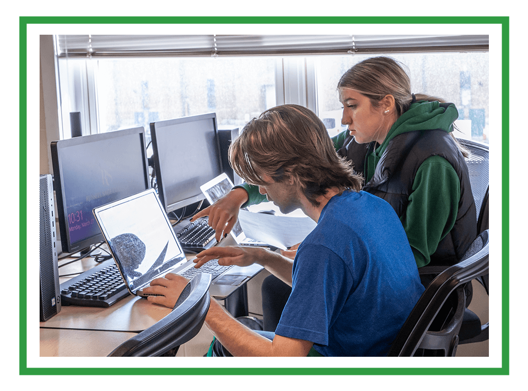 Two students work together on laptops.